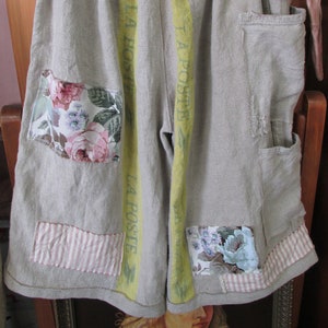 May include: Gray linen shorts with yellow and green stripes and the text "LA POSTE" repeated down the sides. The shorts have several patches of floral fabric and a red and white gingham patch.