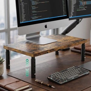 May include: A rectangular monitor stand featuring a rustic brown wood-grain surface supported by four adjustable black metal legs. The stand elevates a silver computer monitor, with visible height adjustment holes on the legs and a graphic icon.