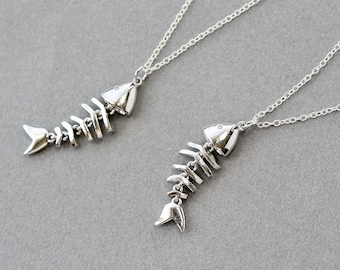 May include: Two silver necklaces with fish bone pendants. The pendants are detailed and realistic, with a silver finish.