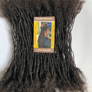 May include: A bundle of black human hair dreadlocks. The dreadlocks are long and thick, and they are arranged in a neat pile. A small card with the text "Dreadlocksbossuk 100% Human Locs Worldwide Shipping 5 Star Quality" is visible in the image.