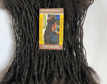 Può includere: Un pacchetto di dreadlock di capelli umani neri. Le dreadlock sono lunghe e spesse e sono disposte in una pila ordinata. Una piccola carta con il testo "Dreadlocksbossuk 100% Human Locs Worldwide Shipping 5 Star Quality" è visibile nell'immagine.