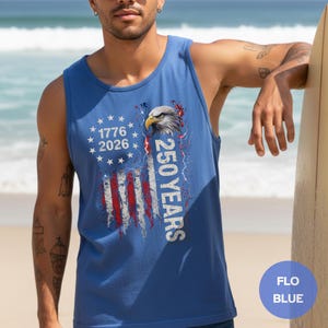 The image showcases a Comfort Colors 9360 Midweight Tank Top featuring a patriotic design. The shirt prominently displays an eagle, the years "1776" and "2026," and a distressed American flag motif. This stylish T-shirt is available in nine colors and sizes ranging from S-3XL, making it a perfect choice for celebrating American pride during Independence Day, family gatherings, or casual outings. The heavyweight fabric ensures comfort and durability, making it an ideal addition to any wardrobe.