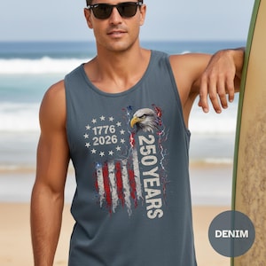 The image showcases a Comfort Colors 9360 Midweight Tank Top featuring a patriotic design. The shirt prominently displays an eagle, the years "1776" and "2026," and a distressed American flag motif. This stylish T-shirt is available in nine colors and sizes ranging from S-3XL, making it a perfect choice for celebrating American pride during Independence Day, family gatherings, or casual outings. The heavyweight fabric ensures comfort and durability, making it an ideal addition to any wardrobe.