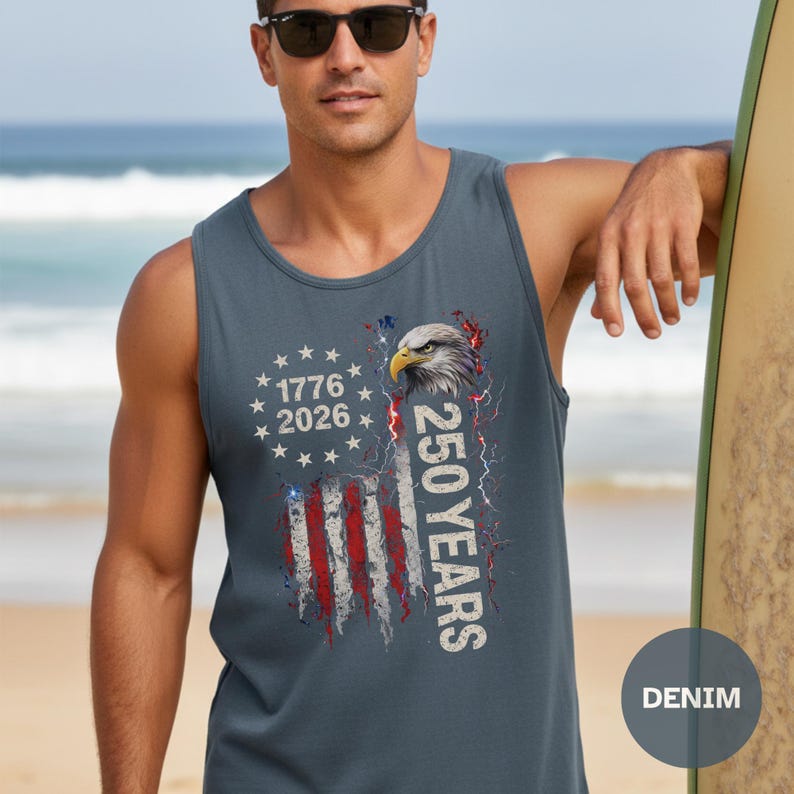 The image showcases a Comfort Colors 9360 Midweight Tank Top featuring a patriotic design. The shirt prominently displays an eagle, the years "1776" and "2026," and a distressed American flag motif. This stylish T-shirt is available in nine colors and sizes ranging from S-3XL, making it a perfect choice for celebrating American pride during Independence Day, family gatherings, or casual outings. The heavyweight fabric ensures comfort and durability, making it an ideal addition to any wardrobe.