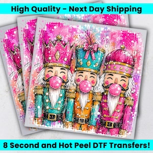 May include: A DTF transfer sheet featuring three nutcracker figures wearing crowns and uniforms in shades of pink, teal, and orange. Each nutcracker has a white beard, a black mustache, and is blowing a large, round, bright pink bubble gum bubble.