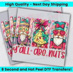 May include: A DTF transfer sheet featuring three colorful illustrations: a nutcracker with tree-shaped glasses, a decorated Christmas tree with a large pink bow, and a nutcracker with heart-shaped glasses. The text reads Y'ALL ARE NUTS.