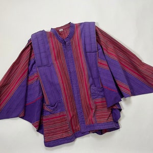 May include: A purple and red striped shirt with a mandarin collar and long sleeves. The shirt has a unique design with multiple panels and pockets.