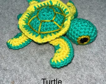 May include: A handmade crochet turtle in shades of green and yellow. The turtle's shell is green with yellow edging and gold-colored stitching. The text "Turtle crochet pattern" is displayed below the turtle.