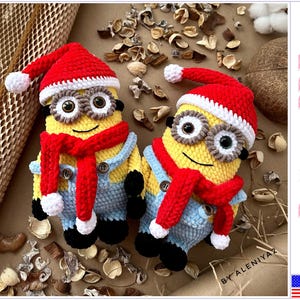 May include: Two crocheted Minion toys wearing red and white Santa hats and scarves. The Minions are wearing blue overalls and have black eyes and yellow bodies.