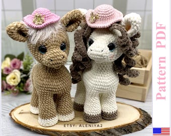 May include: Two crocheted plush toy horses wearing pink hats. The horse on the left is brown and the horse on the right is white. Both horses have brown yarn for their manes and tails. The horses are sitting on a wooden slice.