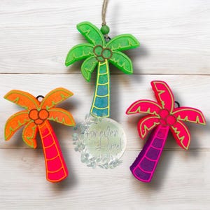 May include: Three palm tree ornaments featuring bright neon colors. One is green with a blue trunk, one is orange with a pink trunk, and one is pink with a purple trunk. Each has a brown coconut cluster and a hanging loop. A logo reads Forever Hazel.