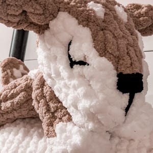 May include: A plush brown and white deer toy with a black nose and eyes. The deer is made of a soft, fluffy material and has a textured surface.