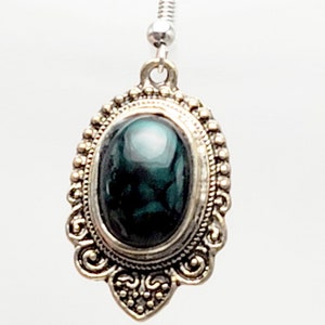 May include: Silver dangle earrings with a green oval stone set in a decorative silver frame.