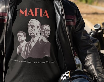 Könnte beinhalten: Schwarzes T-Shirt mit dem Wort "MAFIA" in Rot und einem Graustufenbild von drei Männern. Das Shirt hat auch den Text "FAMILY COMES FIRST, NO MATTER THE COST". Die Person trägt eine schwarze Lederjacke, blaue Jeans und hält einen schwarz-weiß karierten Helm.