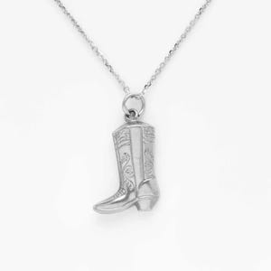 Op de afbeelding: Een zilveren ketting met een laarsbedel. De laars is versierd met een gegraveerd bloemenpatroon.
