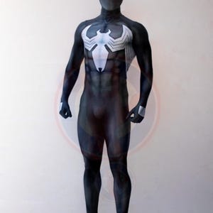 May include: A full-body black spandex costume featuring a large white spider emblem on the chest and back. The suit includes a matching mask with white eye lenses and silver accents on the hands, covering the wearer from head to toe in one piece.