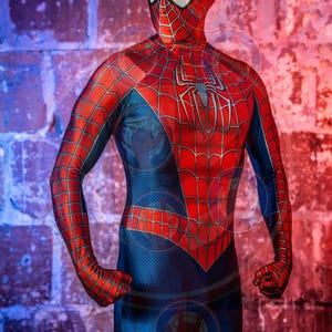 Op de afbeelding: Een rood en blauw spandex kostuum met een spinnenwebontwerp. Het kostuum heeft een masker met witte ogen en een rood spinnenwebontwerp.