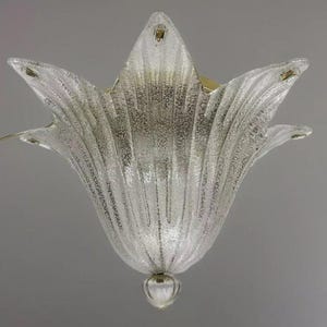 Può includere: Un lampadario da soffitto in vetro trasparente a forma di fiore con una superficie testurizzata e una base in metallo dorato.