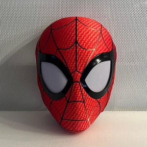 May include: A red and black Spider-Man mask with a mesh eye covering. The mask has a detailed web design.