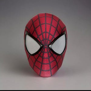 Op de afbeelding: Een rood en zwart Spider-Man-masker met een gaasoogontwerp.