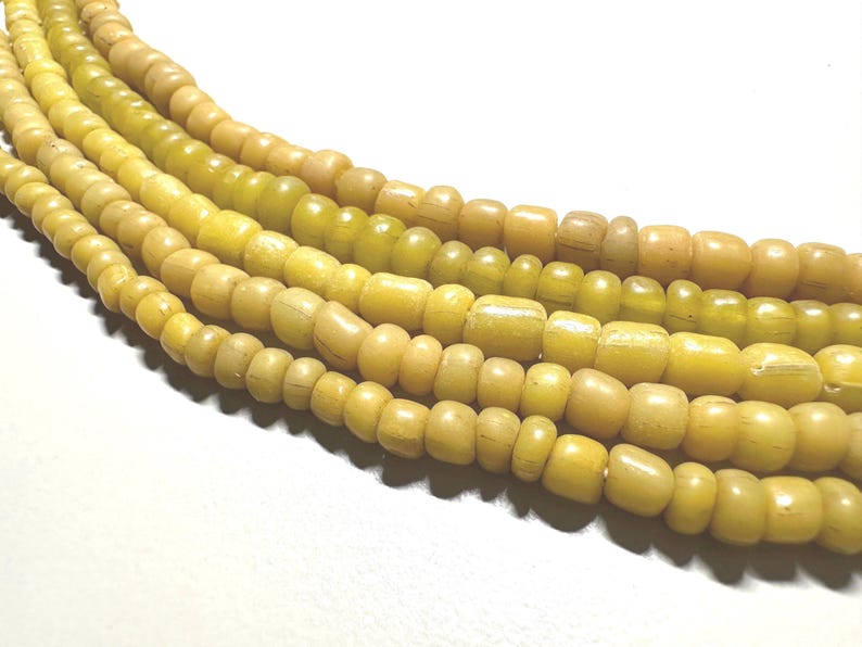 Pu&ograve; includere: Pi&ugrave; fili di perline color giallo, ciascuna con una forma arrotondata e leggermente irregolare. Le perline variano dal giallo chiaro a una tonalit&agrave; dorata pi&ugrave; intensa. Le perline sono infilate, creando un motivo strutturato e visivamente accattivante.