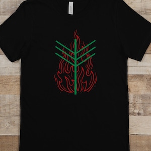 May include: Black t-shirt featuring a green and red graphic of a stylised flame with a tree inside.