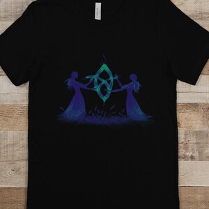 May include: Black t-shirt featuring a green and blue design of two figures holding hands around a symbol.