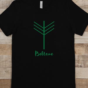 May include: Black t-shirt featuring a green stylised tree design with the word "Beltane" printed below it.