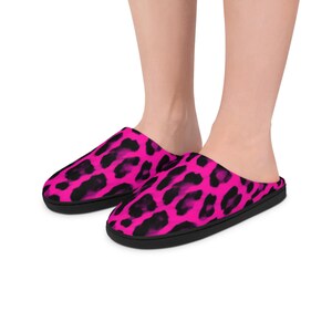 Op de afbeelding: Een paar roze en zwarte pantoffels met luipaardprint. De pantoffels hebben een zwarte zool en een instapontwerp. Het luipaardpatroon bedekt het gehele bovenoppervlak van de pantoffels.