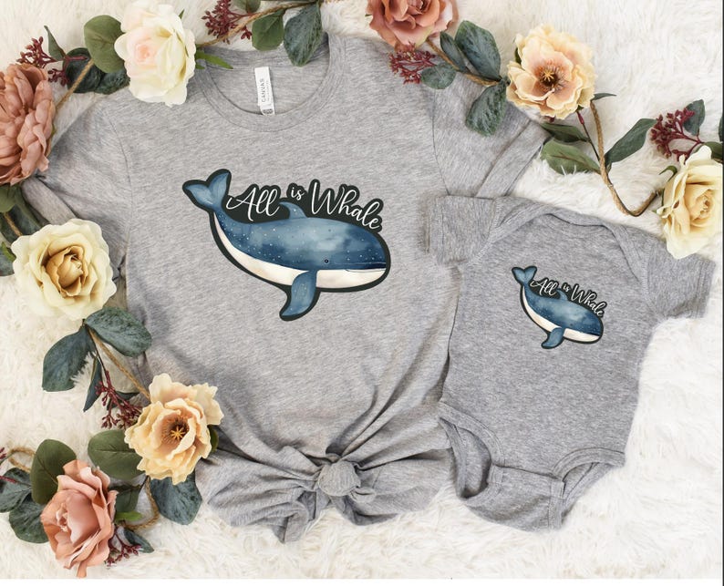 Op de afbeelding: Een grijs T-shirt en een grijs rompertje met een blauwe walvisafbeelding en de tekst "All is Whale".