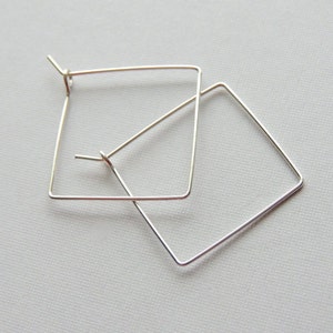 May include: A pair of silver square hoop earrings. The earrings are simple and elegant.