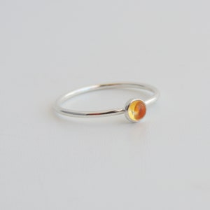 Peut inclure: Une bague en argent avec une pierre ronde orange.