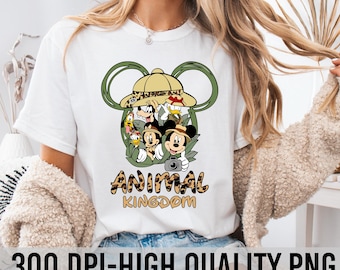 Könnte beinhalten: Weißes T-Shirt mit einem grünen Mickey-Mouse-Ohren-Design. Die Ohren haben einen Safarihut mit einem braunen und gelben Leopardenmusterband. In den Ohren befinden sich Mickey Mouse, Donald Duck, Goofy und Pluto. Der Text "Animal Kingdom" befindet sich unter den Ohren in einer braunen und gelben Leopardenmuster-Schrift.