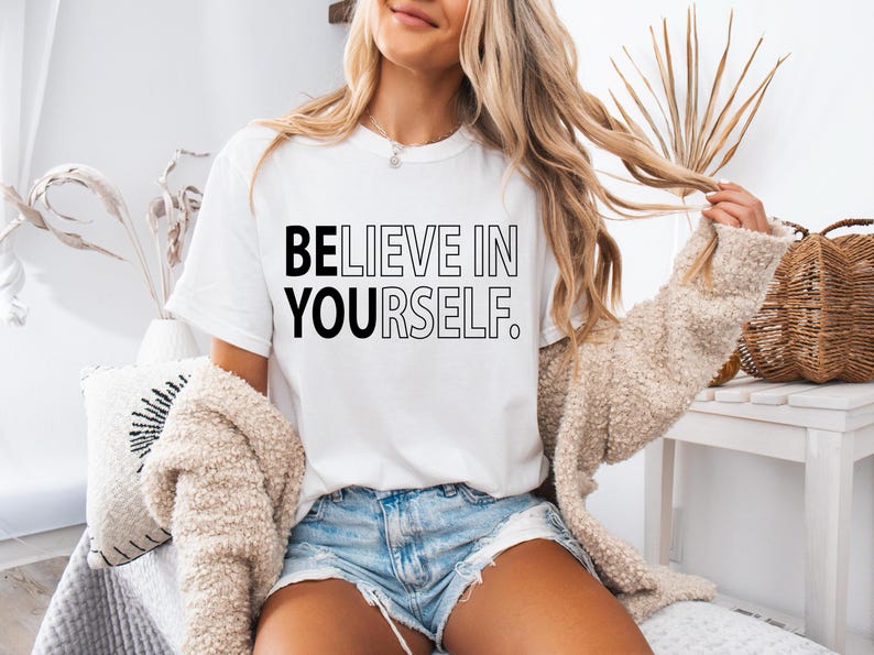Pu&ograve; includere: Una maglietta bianca con la scritta "BELIEVE IN YOURSELF." stampata in nero.