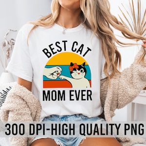 May include: White t-shirt with a retro-style graphic of a cat with a bow giving a high five to a hand. The text "Best Cat Mom Ever" is printed below the graphic.