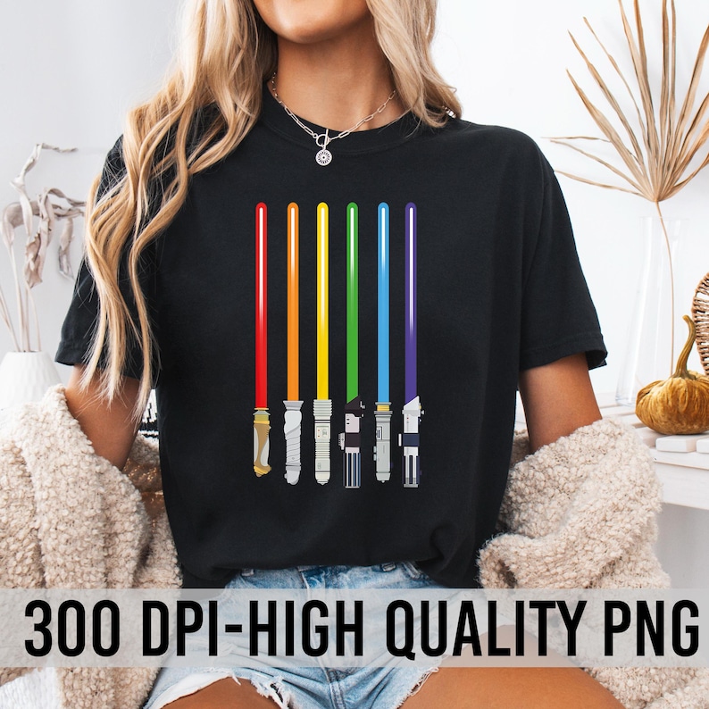 Peut inclure: T-shirt noir avec un motif de six sabres laser color&eacute;s en rouge, orange, jaune, vert, bleu et violet. Les sabres laser sont dispos&eacute;s verticalement. Le texte "300 DPI-HIGH QUALITY PNG" est en bas du t-shirt.