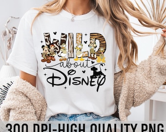 Könnte beinhalten: Weißes T-Shirt mit einem grafischen Design von Disney-Charakteren in Safari-Outfits. Der Text "WILD about DISNEY" ist auf das Shirt gedruckt.