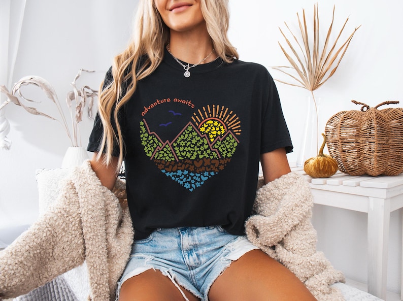 May include: Black t-shirt with a colourful graphic of a mountain range, sun, and the text "adventure awaits".