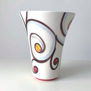 May include: A white ceramic mug with a black handle and the text "But First, Coffee" in a bold, black font. The mug is likely 11 ounces in size and sits on a white surface.