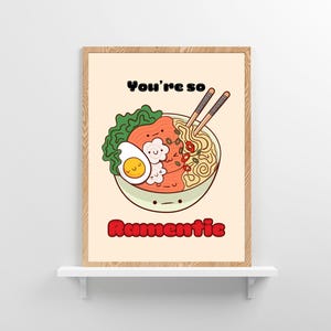 Cute ramen bowl illustration with chopsticks and text 'You're so Ramentic' in a wooden frame on a minimalist shelf.