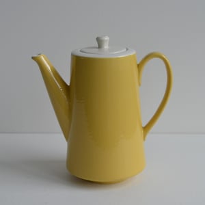 May include: A yellow ceramic teapot with a white rim and lid. The teapot has a curved handle and a spout for pouring. The design is simple and elegant, suitable for serving tea or coffee.