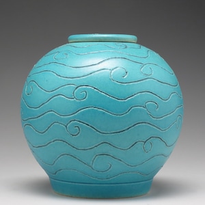 May include: A turquoise ceramic vase with a wavy pattern. The vase is round and has a smooth, glossy finish.