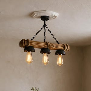 May include: A rustic wooden chandelier with three Edison-style bulbs hangs above a wooden dining table. The light fixture features a dark wood beam, rope detailing, and black metal accents. A vase with greenery sits on the table, with wooden chairs around it.