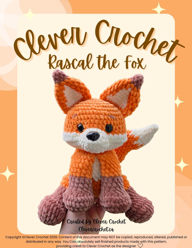 May include: A crocheted fox toy named "Rascal" in shades of orange, white, and mauve. The fox has large ears, a white chest, and mauve paws. The text "Clever Crochet" and "Rascal the Fox" are displayed above the fox. The text "Created by Clever Crochet" and "Clevercrochet.ca" are displayed below the fox.
