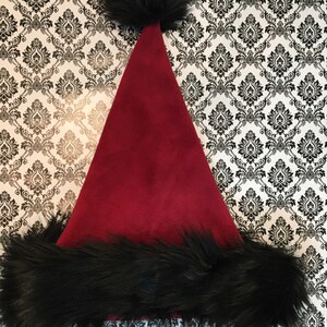 May include: A red velvet Santa hat with a black faux fur trim and pom pom.