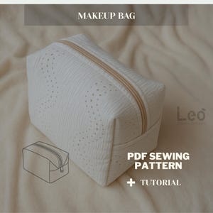 May include: A white makeup bag with a textured surface and a gold zipper. The bag has a rectangular shape and features the text "MAKEUP BAG" at the top. The image also includes a drawing of the bag and the text "PDF SEWING PATTERN + TUTORIAL".
