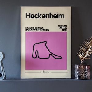 Könnte beinhalten: Ein schwarz-weißes Poster mit dem Text "Hockenheim" in Fettdruck, "Hockenheimring Baden-Württemberg" und "Großer Preis von Deutschland". Das Poster zeigt einen rosafarbenen Hintergrund mit einem schwarzen Umriss einer Rennstrecke.
