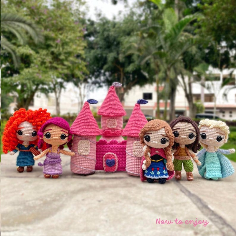 May include: A selection of handmade crochet dolls and a pink castle. The dolls feature characters with red, brown, and blonde hair, dressed in different outfits. The castle is pink with a heart-shaped door. The text "Now to enjoy" is at the bottom.