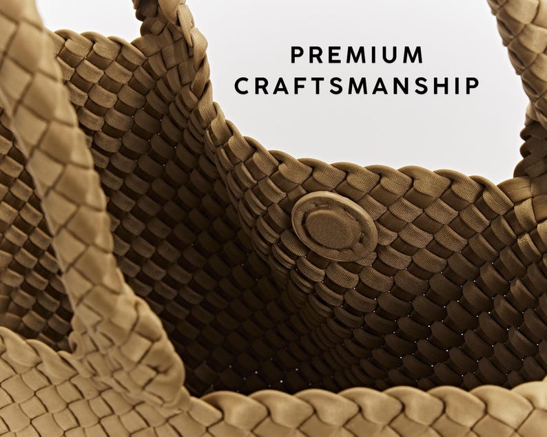 May include: Close-up of a woven tote bag in a light brown color. The bag features a magnetic closure and handles. The text "PREMIUM CRAFTSMANSHIP" is displayed in black letters on a white background.