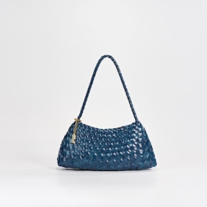 Peut inclure: Un sac à main tressé bleu foncé doté d'une bandoulière tressée et d'une breloque en métal doré attachée sur le côté. Le sac présente une silhouette rectangulaire légèrement incurvée avec un motif entrelacé cohérent sur toute la surface.